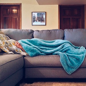 Persona con fiebre tumbada en el sofá