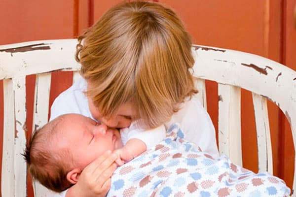 Un niño dándole un beso a su hermano bebé