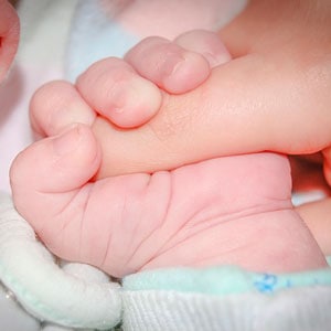 Mano de un bebe agarrando otra mano