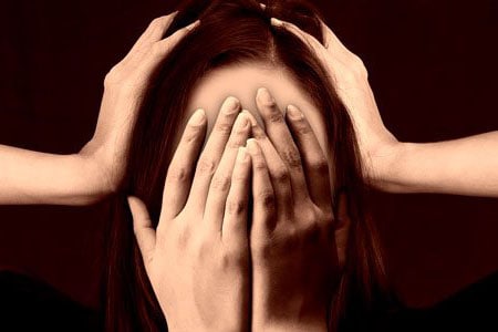 Mujer tapándose el rostro con varias manos a causa del estrés