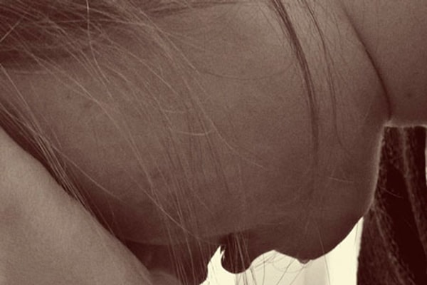 Mujer con una mano sobre la frente y boca abajo, agobiada