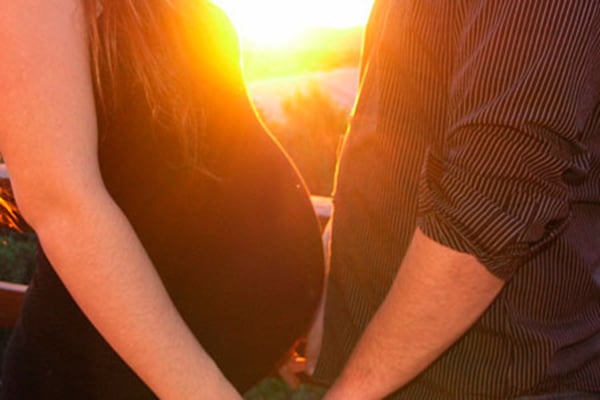 Una mujer embarazada coge de las manos a su pareja