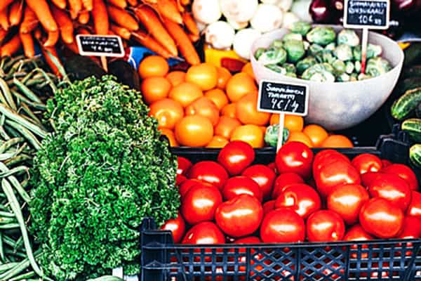 Puesto con verduras, zanahorias, cebollas, ajos, brócoli y pepinos