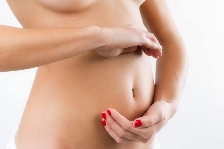 Mujer tiene las dos manos en su vientre, una arriba y otra debajo