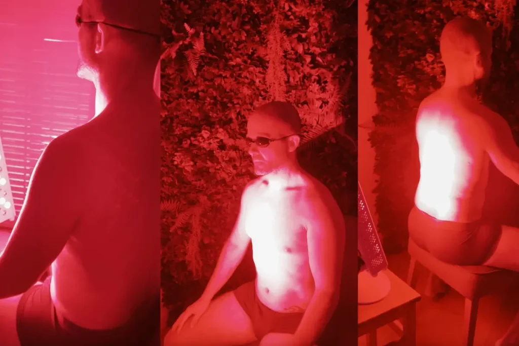 Hombre recibiendo terapia de luz roja sentado frente a un panel de luz infrarroja, utilizando gafas de protección para los ojos.